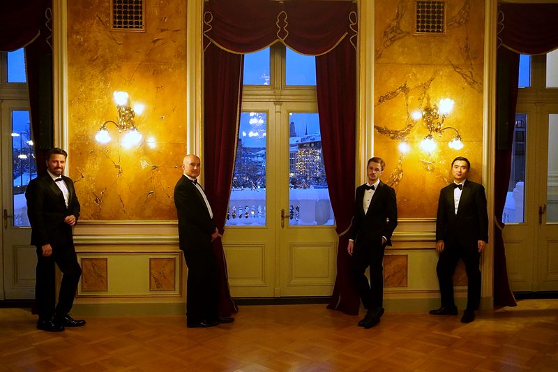 Die Sänger vor goldenen Wänden und roten Vorhängen